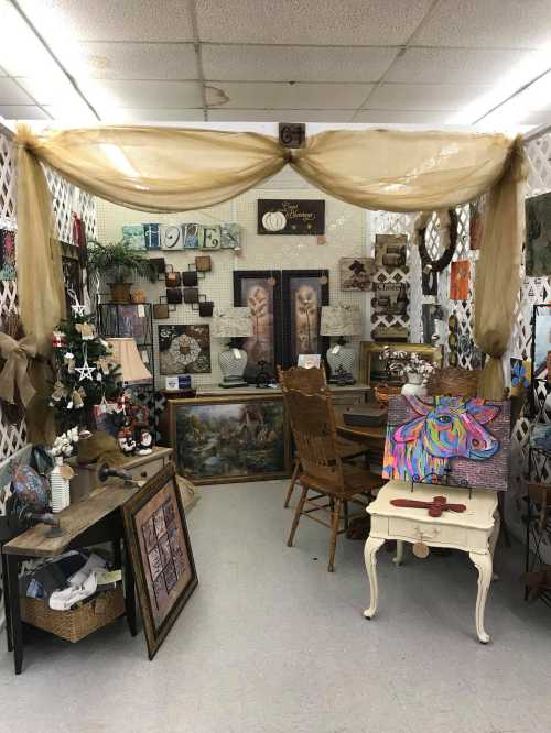 A cozy shop interior featuring decorative items, artwork, and furniture arranged under a draped fabric canopy.