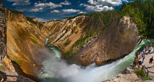 A panoramic view of a river cascading through a canyon, surrounded by lush greenery and dramatic rock formations.