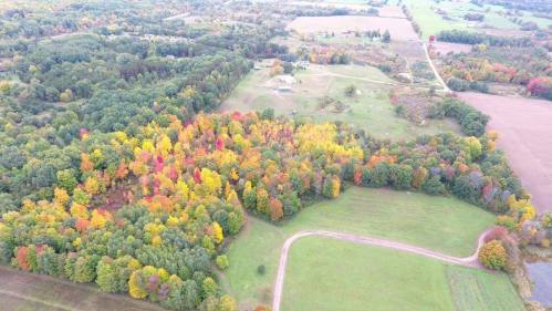 Aerial view of a vibrant autumn landscape with colorful trees and open fields.