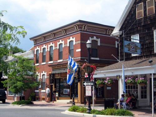 A charming street scene featuring brick buildings, colorful flags, and flower baskets in a quaint town.
