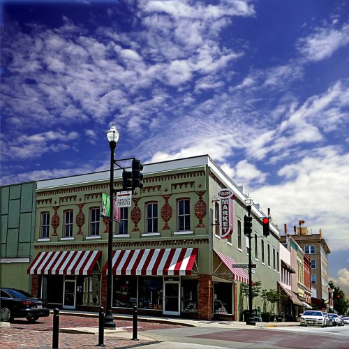 Historic building with a market sign, striped awnings, and a blue sky with clouds in a downtown area.