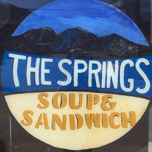 Sign for "The Springs" featuring mountains, with the text "Soupe & Sandwich" in a colorful design.