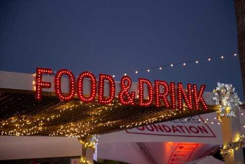 Bright red "FOOD&DRINK" sign illuminated with lights, set against a twilight sky.