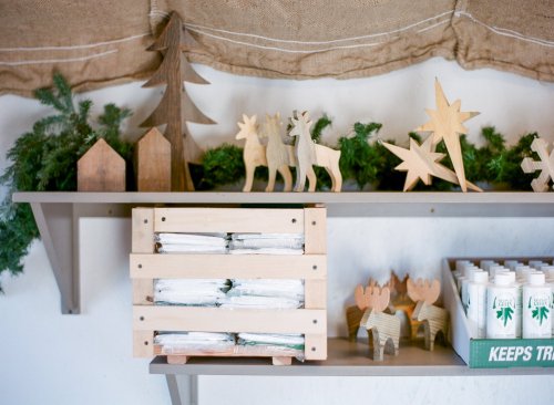 A wooden shelf displays festive decorations, including trees, reindeer, and stars, alongside neatly stacked items in a crate.