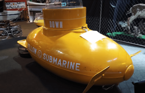 A bright yellow submarine with "YELLOW SUBMARINE" written on the side, displayed indoors.