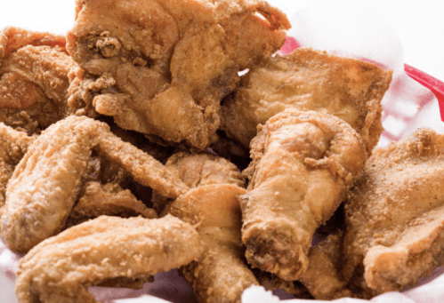 A basket of crispy fried chicken pieces, including wings and drumsticks, arranged appetizingly.