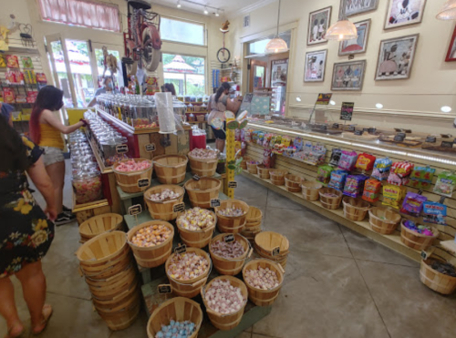 A colorful candy shop filled with baskets of sweets and customers browsing the treats.