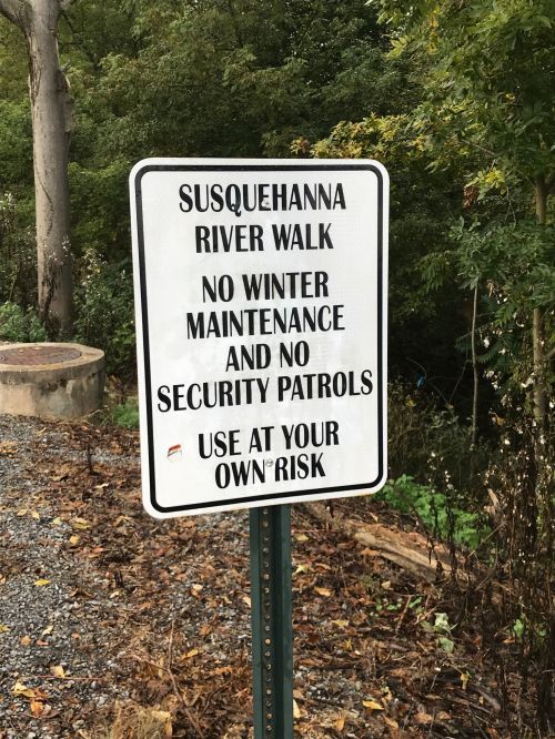 Sign for Susquehanna River Walk stating no winter maintenance or security patrols; use at your own risk.