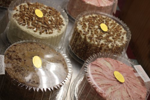 A display of six decorated cakes in clear packaging, featuring various flavors and toppings.