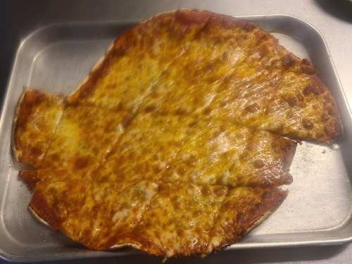 A slightly irregularly shaped cheese pizza on a metal tray, with melted cheese and a golden-brown crust.