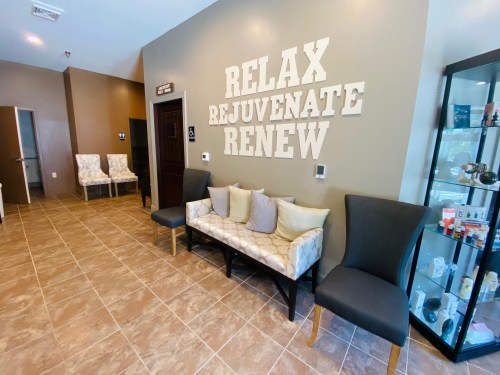 A welcoming interior with a bench, chairs, and a wall displaying the words "Relax, Rejuvenate, Renew."