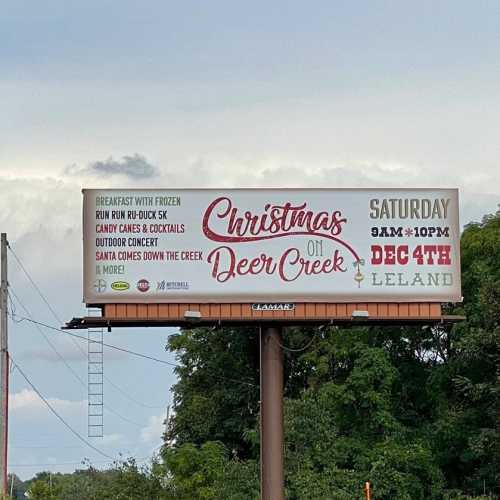 Billboard advertising "Christmas on Deer Creek" event on December 4th, featuring activities and Santa, from 9 AM to 10 PM.