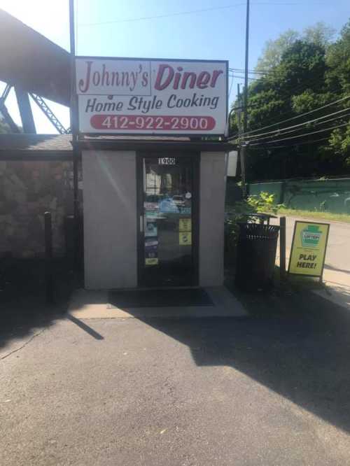 Exterior of Johnny's Diner, featuring a sign for home-style cooking and a phone number, with a play area sign nearby.