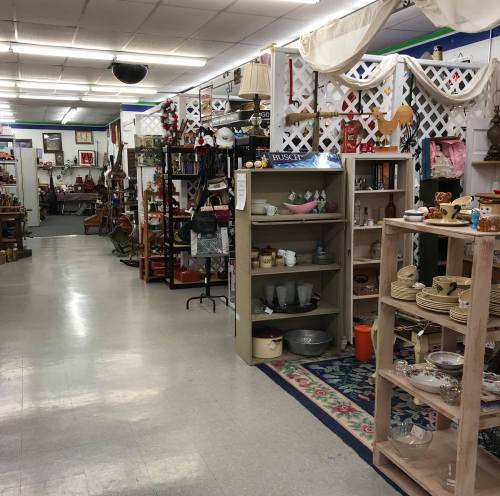A cozy antique shop aisle filled with various vintage items, shelves, and decorative displays.
