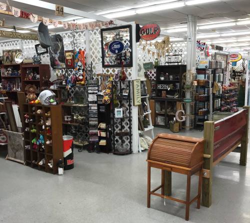 A spacious store aisle filled with various decorative items, shelves, and displays, including furniture and signs.