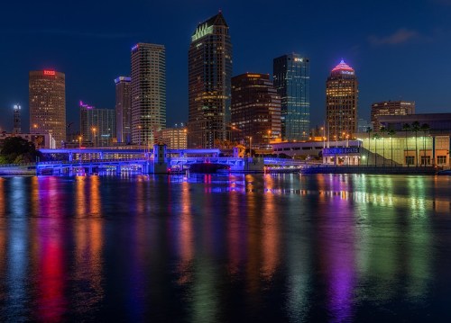 City skyline at night with colorful lights reflecting on the water.