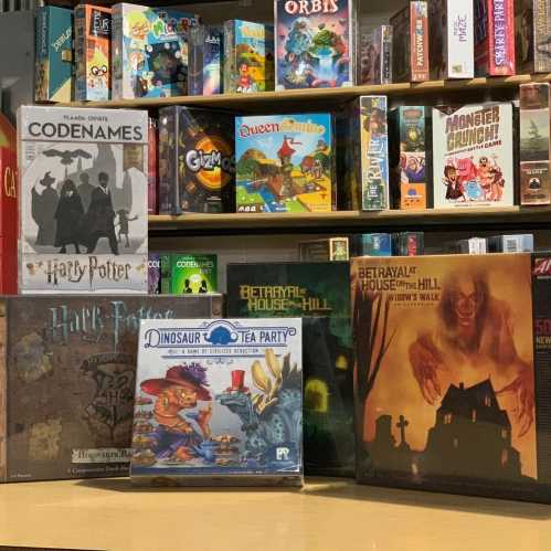 A collection of board games displayed on a shelf, including titles like Harry Potter, Codenames, and Betrayal at House on the Hill.