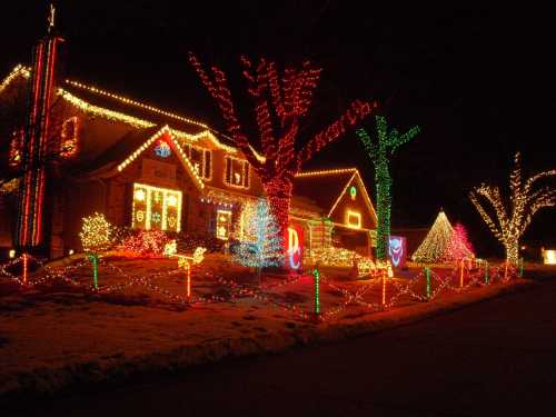 A beautifully decorated house with colorful Christmas lights and festive displays in the yard at night.