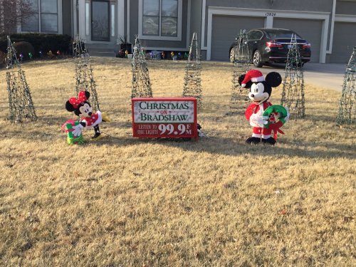 A festive yard display featuring Mickey and Minnie Mouse decorations, with a sign for a Christmas lights event.