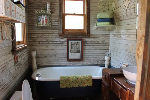 Cozy bathroom featuring a vintage clawfoot tub, wooden accents, and neatly arranged towels and toiletries.