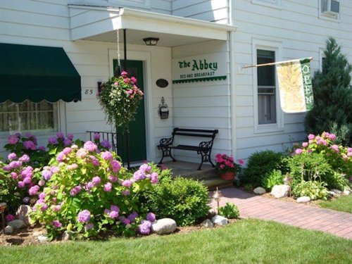 Charming bed and breakfast entrance with a sign, flowers, and a welcoming "Open" flag.
