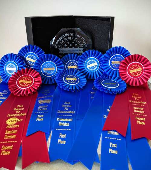 A collection of blue and red ribbons and an award plaque, showcasing various competition placements and divisions.