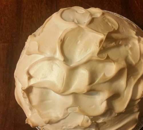 A close-up of a pie topped with swirls of creamy, light-colored meringue.