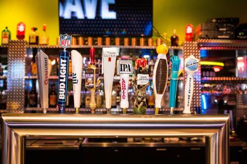 A row of beer taps featuring various brands in a vibrant bar setting.