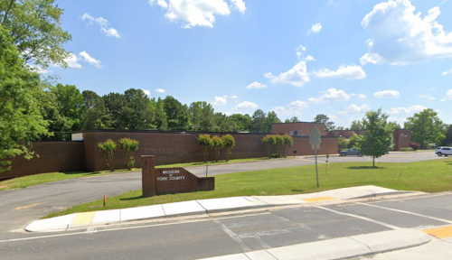 A brown building with "Museum York County" signage, surrounded by trees and a clear blue sky.