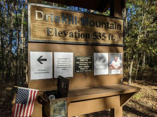 Sign for Driskill Mountain, elevation 535 ft, with information about a special tribute and a photo of a scout.