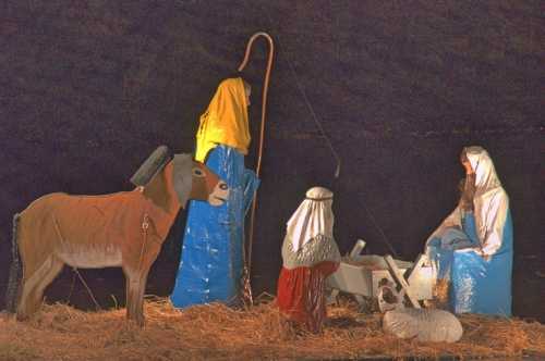 Nativity scene with figures of Mary, Joseph, and baby Jesus, surrounded by animals in a straw-filled setting.