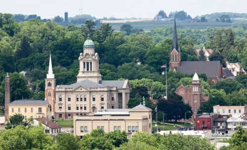 A scenic view of a small town with historic buildings, churches, and lush green hills in the background.