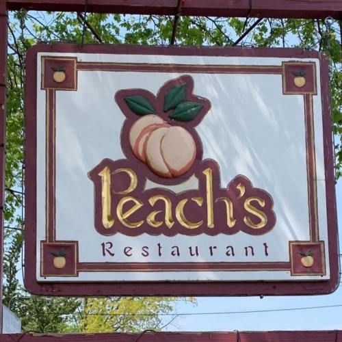 Sign for Peach's Restaurant featuring a peach graphic and decorative border.