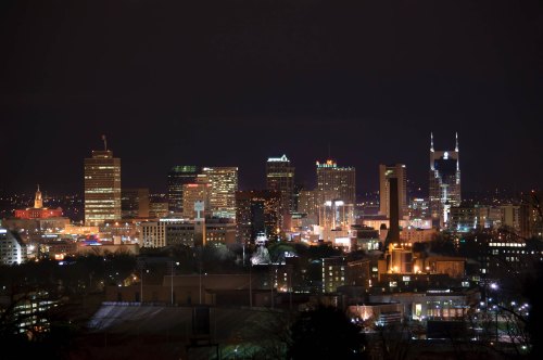City skyline at night, featuring illuminated buildings and a clear sky.