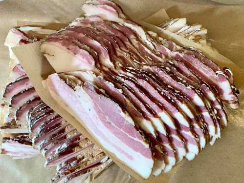 Sliced bacon arranged neatly on parchment paper, showcasing layers of meat and fat.