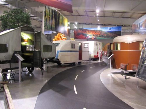A museum exhibit featuring various vintage trailers and campers arranged along a winding path.
