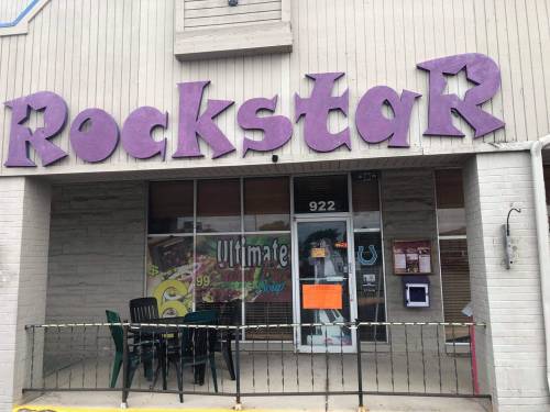 Storefront of "Rockstar" with purple signage, featuring a window display and outdoor seating.