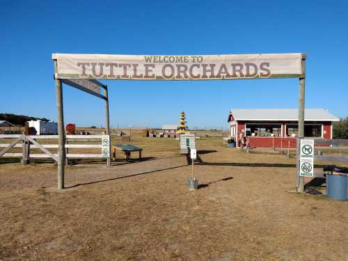 Sign welcoming visitors to Tuttle Orchards, with a clear blue sky and farm buildings in the background.