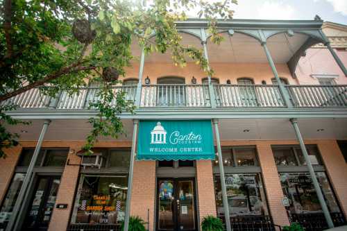 Exterior of the Canton Museum Welcome Center, featuring a green awning and a balcony surrounded by trees.