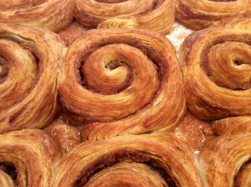 Close-up of freshly baked cinnamon rolls with golden-brown swirls and a sugary filling.