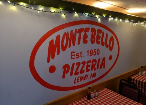 Interior of Montebello Pizzeria in Lemay, MO, featuring a red and white sign on the wall and checkered tablecloths.