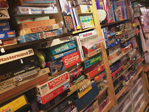 A colorful collection of board games stacked on shelves, showcasing various classic and modern titles.