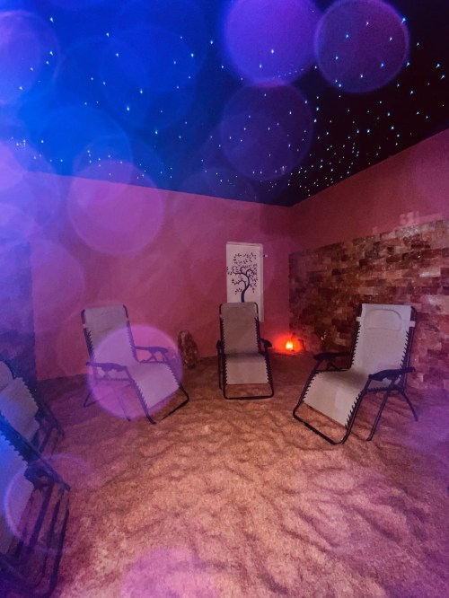 A tranquil room with reclining chairs, soft lighting, and a starry ceiling, designed for relaxation and wellness.