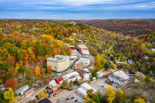 Aerial view of a colorful autumn landscape with a small town nestled among vibrant trees and rolling hills.