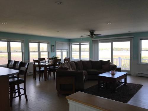 Bright, airy living room with large windows overlooking a water view, featuring a sofa, coffee table, and dining area.