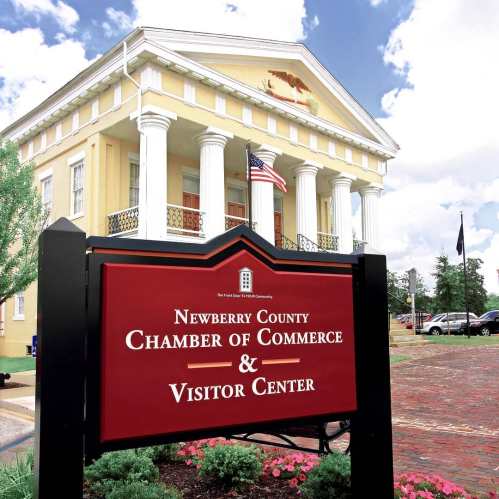 Sign for the Newberry County Chamber of Commerce and Visitor Center in front of a historic building with columns.