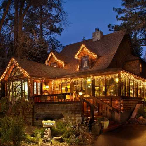 A cozy cabin illuminated with warm lights, surrounded by trees, with a "vacancy" sign at the entrance.