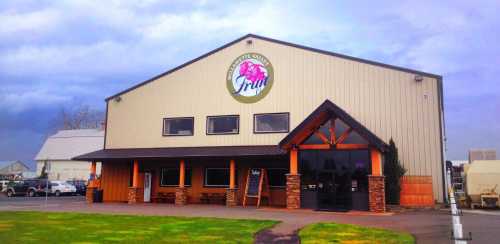 A large, modern building with a sign reading "Fruit" and a welcoming entrance, set against a cloudy sky.