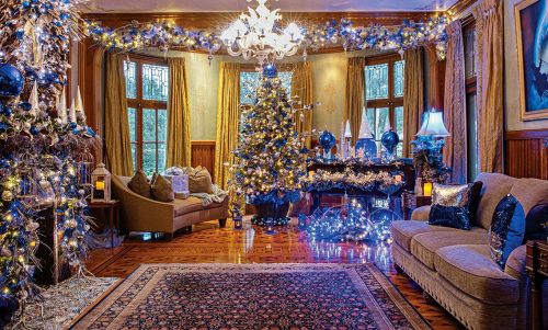 A beautifully decorated living room for Christmas, featuring a tree, lights, and elegant furnishings.