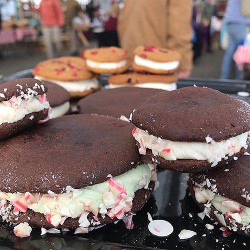 Close-up of chocolate whoopie pies filled with mint cream and crushed peppermint, displayed at a market.
